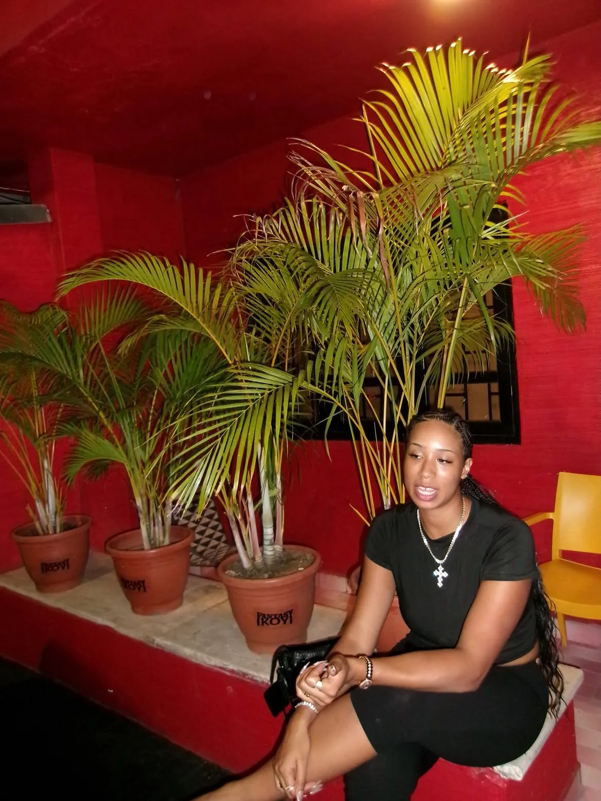 A guest seated beside plants against a red wall