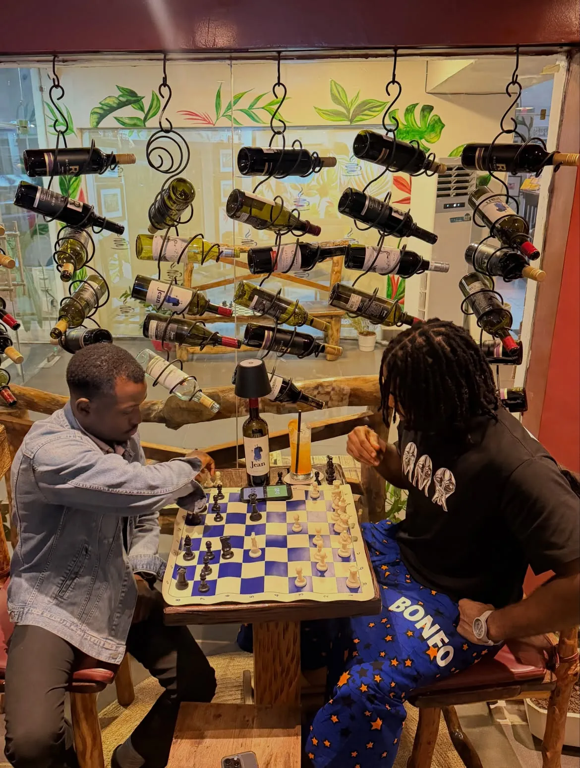 Players studying a purple and cream chessboard