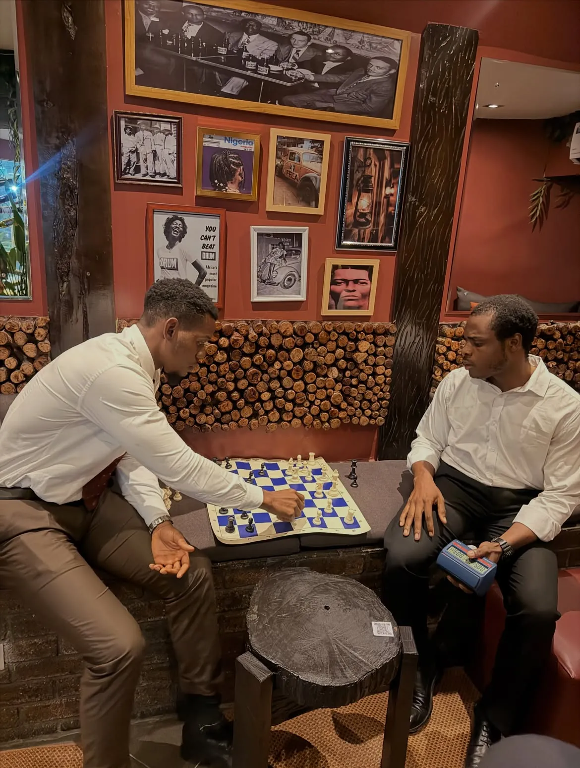 Two guests playing at a table beneath framed art